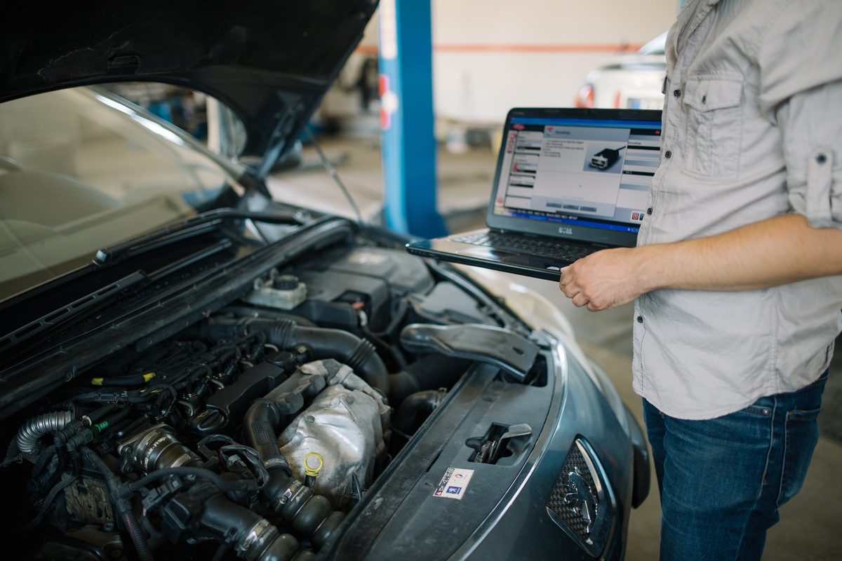 Technician running a computerized diagnostic on a vehicle's engine